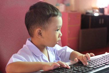 Genç bir çocuk bilgisayar klavyesine bağlanır, konsantrasyon ve merak gösterir. Bu an, erken öğrenmenin ve dijital keşiflerin özünü yakalar..