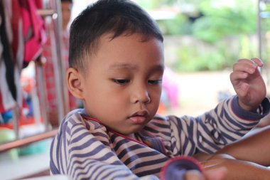 Genç bir çocuk, masumiyetini ve merakını gösteren eğlenceli bir aktiviteye derinden odaklanmıştı. Görüntü, sıradan bir ortamda çocukluk keşiflerinin huzurlu bir anını yakalıyor..