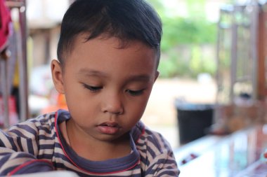 Düşünceli genç bir çocuk, masumiyetini ve merakını göstererek huzurlu bir ortamda kendini bir göreve kaptırır. Çocukluk ve eğitim konulu temalar için mükemmel.