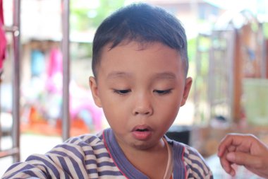 Düşünceli genç bir çocuk içeride yaratıcı bir aktiviteyle meşgul, masumiyet ve merak gösteriyor. Onun odaklanmış ifadesi çocukluk keşfi ve neşesinin özünü yakalar..