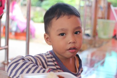 Meraklı bir yüzü olan genç bir çocuk dışarıda yemekten hoşlanır. Sahne, çocukluğun ve masumiyetin özünü sıcak ve davetkar bir ortamda yakalıyor..