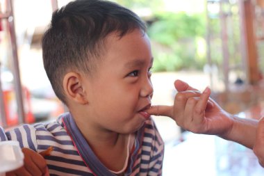 Neşeli bir çocuk hafif bir etkileşimle atıştırmanın tadını çıkarır. Bu samimi an masumiyet ve mutluluğu yakalıyor, neşeli çocukluğu vurguluyor..
