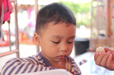 Çizgili pijamalarıyla düşünceli genç bir çocuk, açık havada bir anlık masumiyet ve neşe gösterisi yaparak aperatiflere odaklanıyor..
