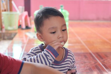 Küçük bir çocuk evde oturup, zevkle atıştırmanın tadını çıkarıyor. Parlak ortam ve neşeli ifade çocukluk anılarının özünü yakalar..