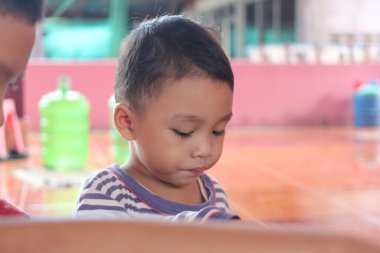 Düşünceli bir çocuk renkli kapalı bir ortamda sessiz bir oyun oynar. Sahne, neşeli bir atmosferde gençliğin masumiyetini ve keşiflerini yakalıyor..