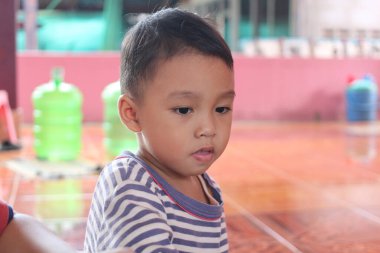 İçeride masum bir ifadeyi sergileyen düşünceli genç bir çocuğun yakın plan portresi. Renkli arka plan, çocukluk anılarını vurgulayan canlı bir atmosfer yaratıyor..