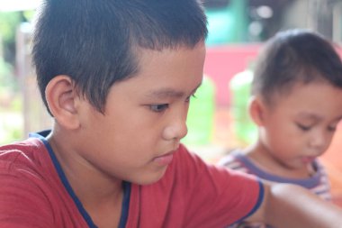 Düşünceli genç bir çocuk, çocukluk konsantrasyonu ve keşiflerinin güzelliğini gündelik bir ortamda sergileyen yaratıcı bir göreve derinden odaklanır..