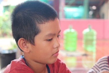 Derin konsantrasyonu yansıtan canlı bir ortamda düşünceli bir çocuğun portresi. Görüntü gençliği ve masumiyeti yansıtıyor..