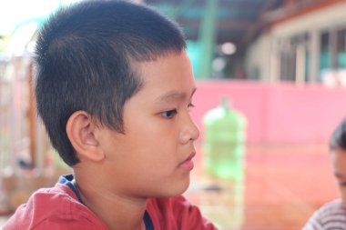 Profilde düşünceli bir çocuk, düşüncelere dalmış. Onun odaklanmış ifadesi çocukluk merakı ve masumiyetinin özünü renkli bir kapalı mekan ortamında yakalıyor..