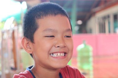 Neşeli genç bir çocuk neşeli, güneşli bir ortamda saf neşe ve masumiyet göstererek gülümsüyor. Işıl ışıl ifadesi mutluluk ve pozitiflik taşıyor..