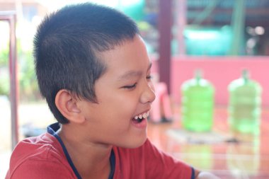 Bu görüntü, neşeli bir gencin gülüşünü ve samimi bir mutluluk anını görüntülüyor. Hareketli ortam, oyun ve masumiyet duygusunu arttırır..