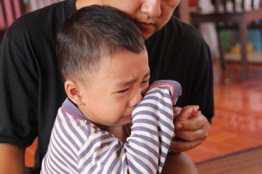 Zor durumdaki bir çocuğu yakalayan, mütevazı bir ev ortamında bir bakıcı tarafından teselli edilen yürek burkan bir an. Üzüntü ve destek duyguları güzel bir şekilde ifade edilir..