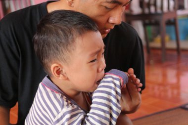 Dokunaklı bir an, bir bakıcı tarafından teselli edilirken ağlayan bir çocuğu yakalar. Yakın çekim derin duyguları ve ebeveyn desteğinin özünü gözler önüne seriyor..