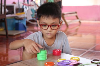 Genç bir çocuk renkli istifleme oyuncaklarıyla oynar, ev ortamında odak ve yaratıcılık gösterir. Bu resim çocukluk gelişimindeki önemli anları yakalar.