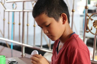 Genç bir çocuk, beyaz bir oyuncak nesneyle oynamaya derinden odaklanır. Ev içi aktiviteler sırasında konsantrasyon ve neşe gösterir..