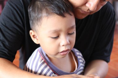 Bir çocuk ve ebeveyn arasındaki güçlü bağı gözler önüne seren, yakın ve samimi bir anda sevgi ve desteği yansıtan iç açıcı bir sahne..