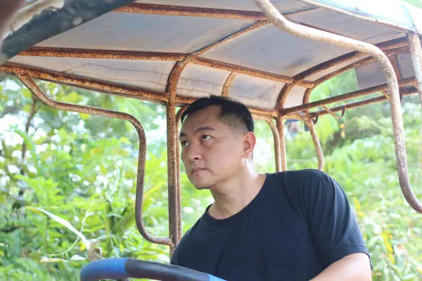 Bir adam yemyeşil ve kırsal alanlarda kendini adamış ve sıkı çalışan bir aracı verimli bir açık havada sürmeye odaklanır..