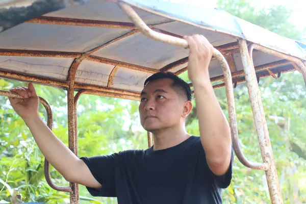 Antika bir araçta durup, düşünceli bir ifadeyle metal parmaklıkları sıkan bir adam. Bereketli yeşilliklerle çevrili, keşif ve macerayı somutlaştırıyor..