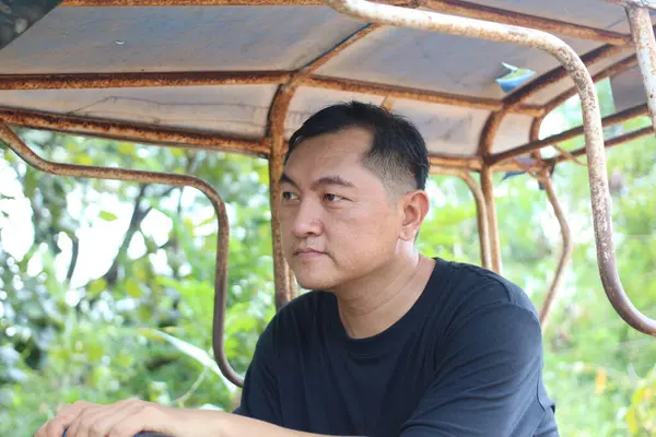 Düşünceli bir adam yemyeşil bir ortamda sakin bir anın tadını çıkararak düşünceli bir ifade sergiliyor. Bu portre doğadaki sükunetin özünü yansıtıyor..