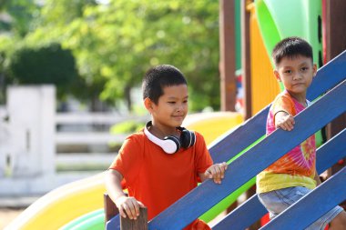 İki neşeli çocuk canlı bir oyun bahçesinde renkli merdivenleri tırmanarak eğleniyor. Sahne çocukluk macerası ve arkadaşlığın özünü yakalıyor..