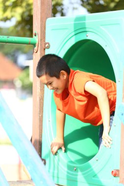 Neşeli bir çocuk oyun alanı kaydırağını keşfediyor, canlı bir açık hava ortamında neşe ve heyecan saçıyor. Çocukluk eğlencesinin özünü yakalar..