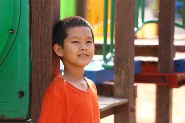 Neşeli genç bir çocuk oyun parkında eğleniyor. Gülüşü çocukluk sevincini yansıtıyor, canlı renkler ve neşeli çevrelerle çevrili..