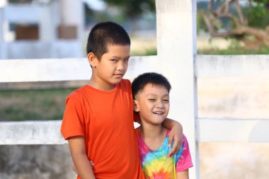 İki çocuk açık havada keyifli bir anın tadını çıkarıyorlar. Arkadaşlıklarını ve neşeli ruhlarını güneşli ve canlı bir ortamda sergiliyorlar..