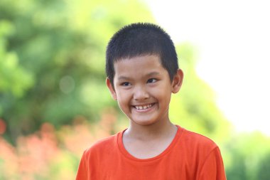 Neşeli bir çocuk, parlak bir gülümsemeyle güneşli bir günün doğal ortamından zevk alır. Görüntü, çocukluk sevincinin ve oyunculuğun özünü yakalar..