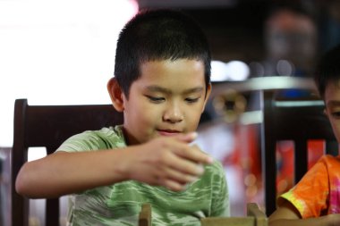 Genç bir çocuk, sıradan bir ev ortamında tahta bloklarla oynamaya odaklanmış. Bu resim yaratıcılığı, keşfi ve neşeli oyunu yakalar..