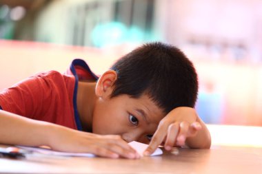 Genç bir çocuk masaya yazılı olarak daldırılır, merakını ve dikkatini gösterir. Bu resim eğitim ortamında çocukluk öğreniminin ve yaratıcılığın özünü yakalar..