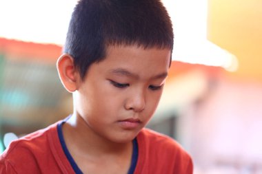 Düşüncelere dalmış genç bir çocuk bir aktivite sırasında ciddi bir ifade sergiliyor. Bu samimi an çocukluğun masumiyetini ve derinliğini yakalar..