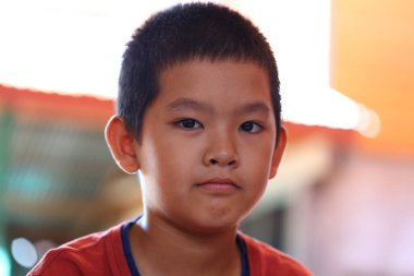 Düşünceli genç bir çocuk ciddi bir ifade sergiliyor, bir anlık tefekkür yakalıyor. Yakın plan portre gençlik deneyiminin masumiyetini ve derinliğini gözler önüne seriyor..