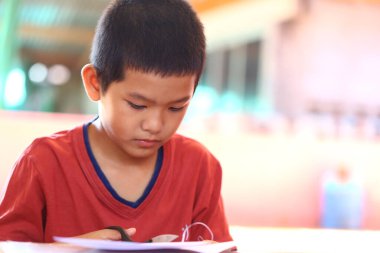 Genç bir çocuk makasla yaratıcı bir projeye, konsantrasyonunu göstermeye ve kapalı alandaki etkinliklerle öğrenmenin zevkine dikkatle odaklanır..