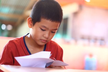 Genç bir çocuk evde oturur, kendini kitap okumaya kaptırır. Konsantrasyon ve merakın ifadesi ile öğrenme sevincini gösterir..