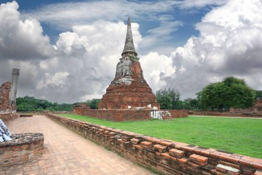Yemyeşil ve dramatik bulutlarla çevrili Ayutthaya Tayland 'daki dramatik gökyüzü altında Wat Phra Si Santhe' deki eski pagoda ve harabeler zengin bir tarihi ve mimari güzelliği gözler önüne seriyor..