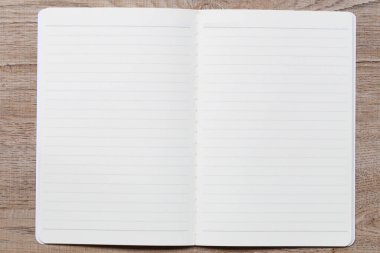 Tahta bir masanın üzerindeki boş defter yazmak ya da çizim yapmak için mükemmel bir yer sunuyor. İlham arayan öğrenciler, yazarlar ve yaratıcılar için idealdir..