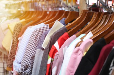 Perakende mağazasında elbise askıları üzerinde canlı bir görüntü, renkler ve desenler karışımı sergiliyor. Moda ve alışveriş ile ilgili konular için ideal.