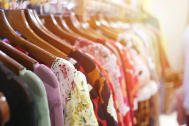 Perakende mağazasında elbise askıları üzerinde canlı bir görüntü, renkler ve desenler karışımı sergiliyor. Moda ve alışveriş ile ilgili konular için ideal.