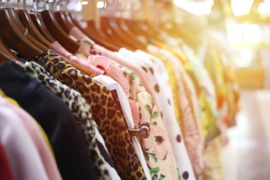 Perakende mağazasında elbise askıları üzerinde canlı bir görüntü, renkler ve desenler karışımı sergiliyor. Moda ve alışveriş ile ilgili konular için ideal.