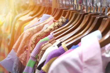 Perakende mağazasında elbise askıları üzerinde canlı bir görüntü, renkler ve desenler karışımı sergiliyor. Moda ve alışveriş ile ilgili konular için ideal.