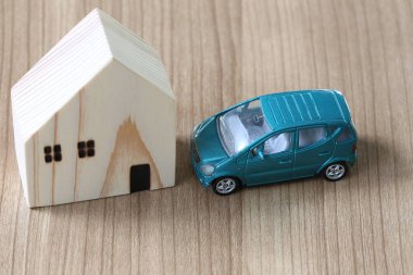 Minyatür ahşap bir ev ve ahşap bir yüzeyde model bir araba, ev ve ulaşım kavramlarını resmetmek için mükemmel bir düzenleme..