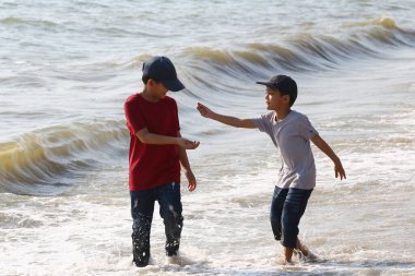 İki çocuk sahilde eğlenceli aktivitelere girişiyor, suyun tadını çıkarırken çocukluklarının neşesini ve masumiyetini yakalıyorlar ve sahilde güneşli bir günün tadını çıkarıyorlar..