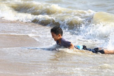 Neşeli bir çocuk sığ sahil suyunda oynarken görülüyor, dalgalar süzülürken neşeyle sıçrıyor, kaygısız yaz eğlencesinin ve çocukluk keşiflerinin ruhunu yakalıyor..