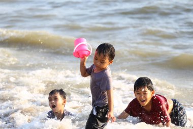 Üç neşeli çocuk sahildeki dalgalarda oynuyorlar, su sıçratıyorlar ve güneşli bir yaz gününün tadını çıkarıyorlar. Gülüşleri çocukluk eğlencesinin ve kaygısız anların ruhunu yakalar..