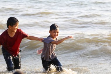 İki neşeli çocuk sığ okyanus suyunda güneşli bir sahilde birlikte vakit geçiriyorlar. Gülüşleri ve oyunculukları çocukluk mutluluğunun unutulmaz bir anını yaratır..