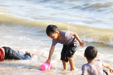 İki çocuk kumsalda güneşli bir günün tadını çıkarıyorlar. Pembe kovayla sığ sularda oynayıp gülüyorlar ve neşeli anılar yaratıyorlar. Sahne çocukluk masumiyetini ve kaygısız eğlenceyi yakalar..