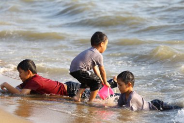 Üç çocuk güneşli bir plajda neşeli bir oyun oynuyorlar, su sıçratıyorlar ve güzel anılar yaratıyorlar. Gülüşleri okyanus kıyısındaki yaz günlerinin kaygısız ruhunu yansıtıyor..
