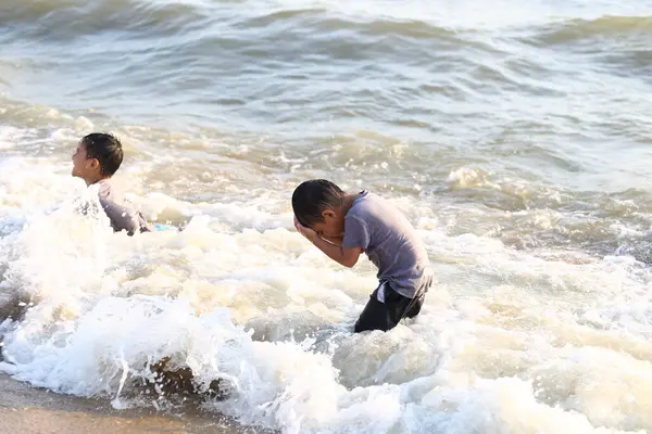 İki genç çocuk sahildeki okyanus dalgalarında neşeyle oynuyorlar, çocukluğun kaygısız masumiyetini ve deniz kenarındaki yaz maceralarının heyecanını gösteriyorlar..