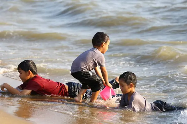 Üç çocuk güneşli bir plajda neşeli bir oyun oynuyorlar, su sıçratıyorlar ve güzel anılar yaratıyorlar. Gülüşleri okyanus kıyısındaki yaz günlerinin kaygısız ruhunu yansıtıyor..