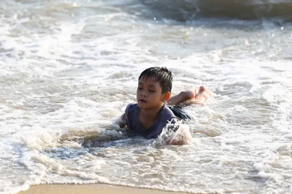 Genç bir çocuk, okyanusun sığ dalgalarında neşeyle oynar. Güneşli bir günde, çocukluğun tasasız ruhunu somutlaştırır. Unutulmaz anılar yaratır..